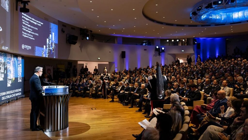 Panoramica dell'Assemblea pubblica di Confitarma, con Mario Zanetti al podio e i partecipanti seduti nell'auditorium.